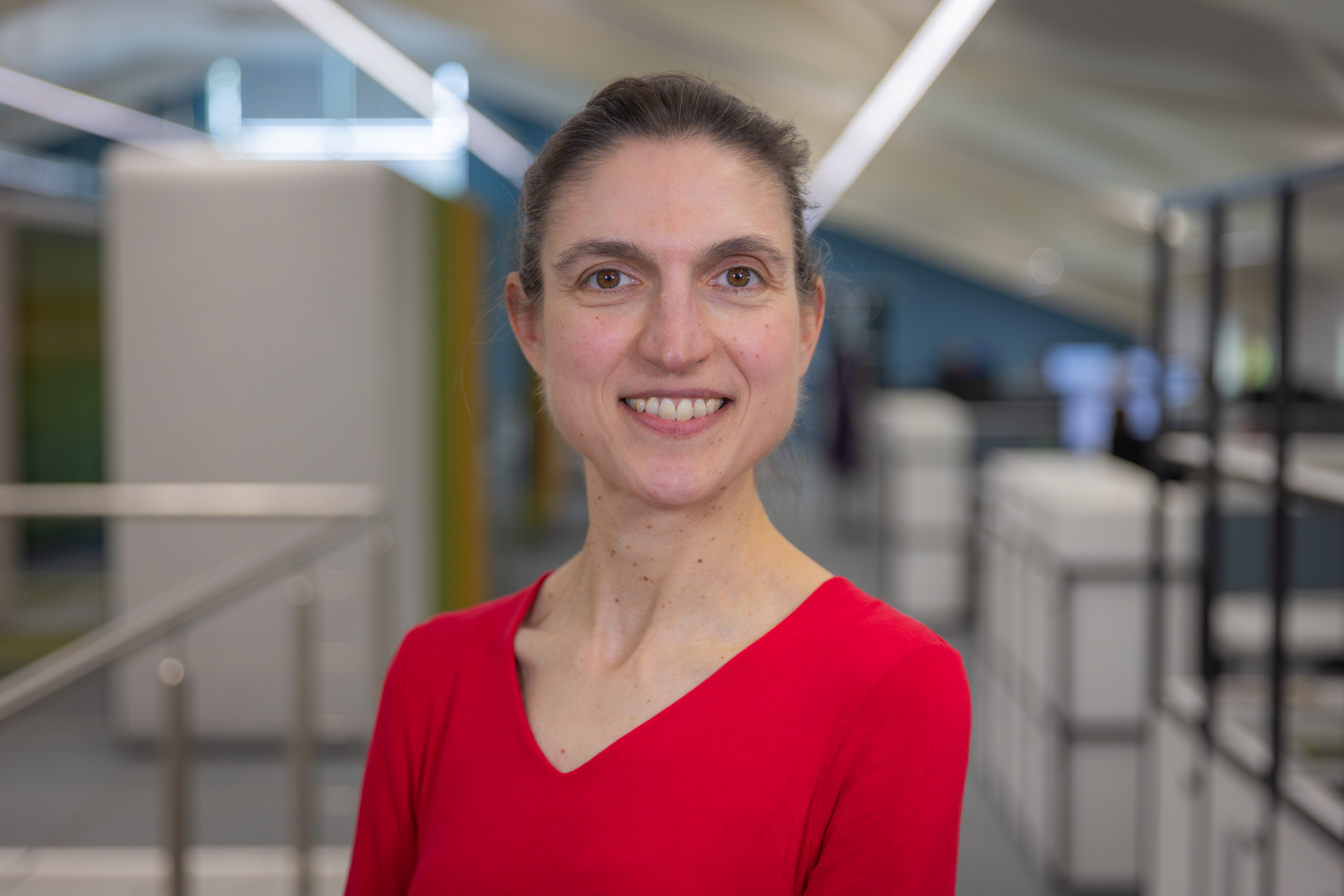 Headshot of Anne-Sophie Bretonnet, a smiling brunette woman in a red top