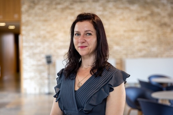 Headshot of Cat Mazilu, a smiling woman with red hair in a navy dress.