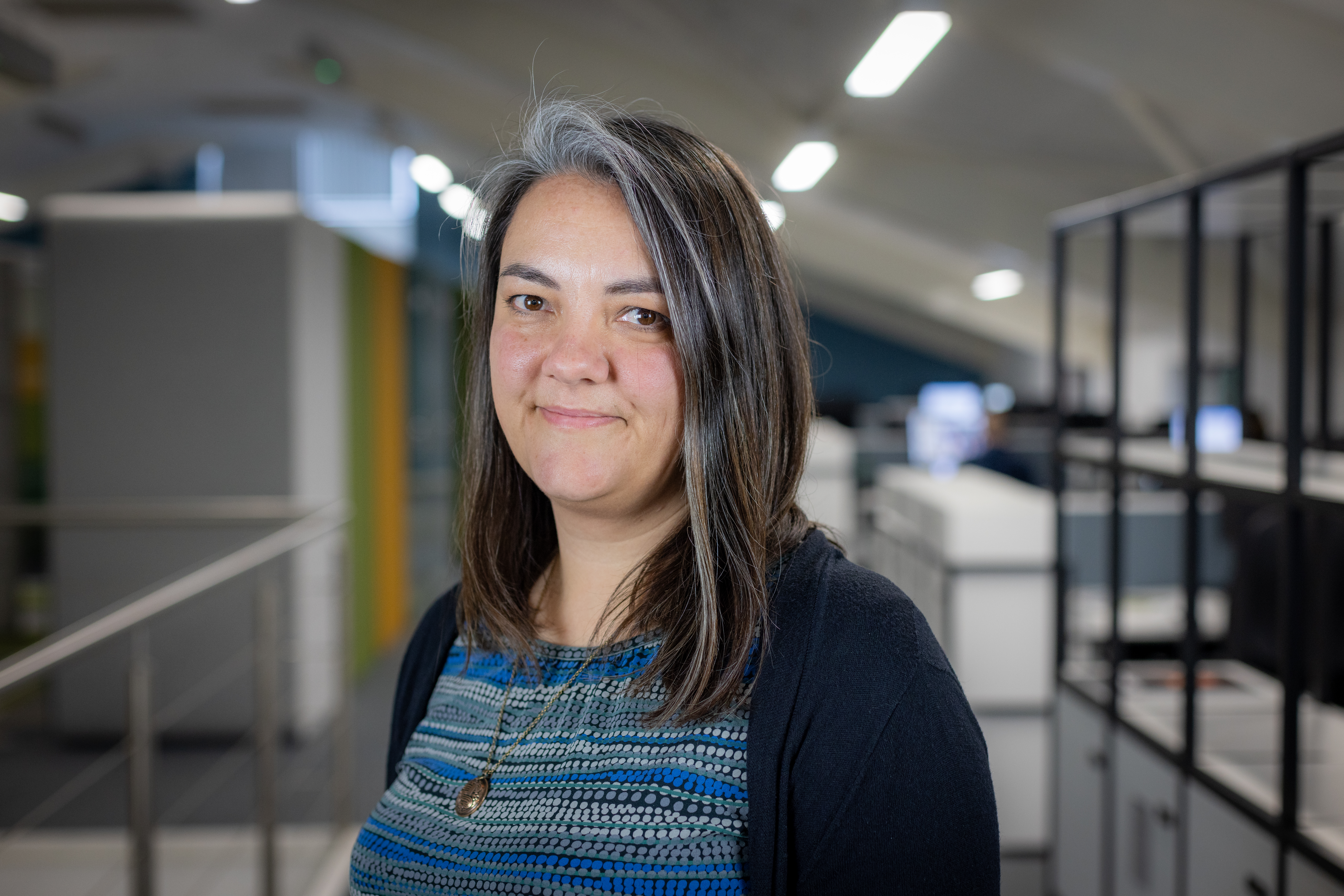 Headshot of Katarina McCartney, a smiling woman in a blue top and black cardigan
