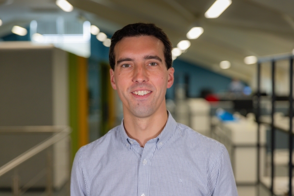 Headshot of Matthew Bennet, a smiling brunette man in a light blue shirt.