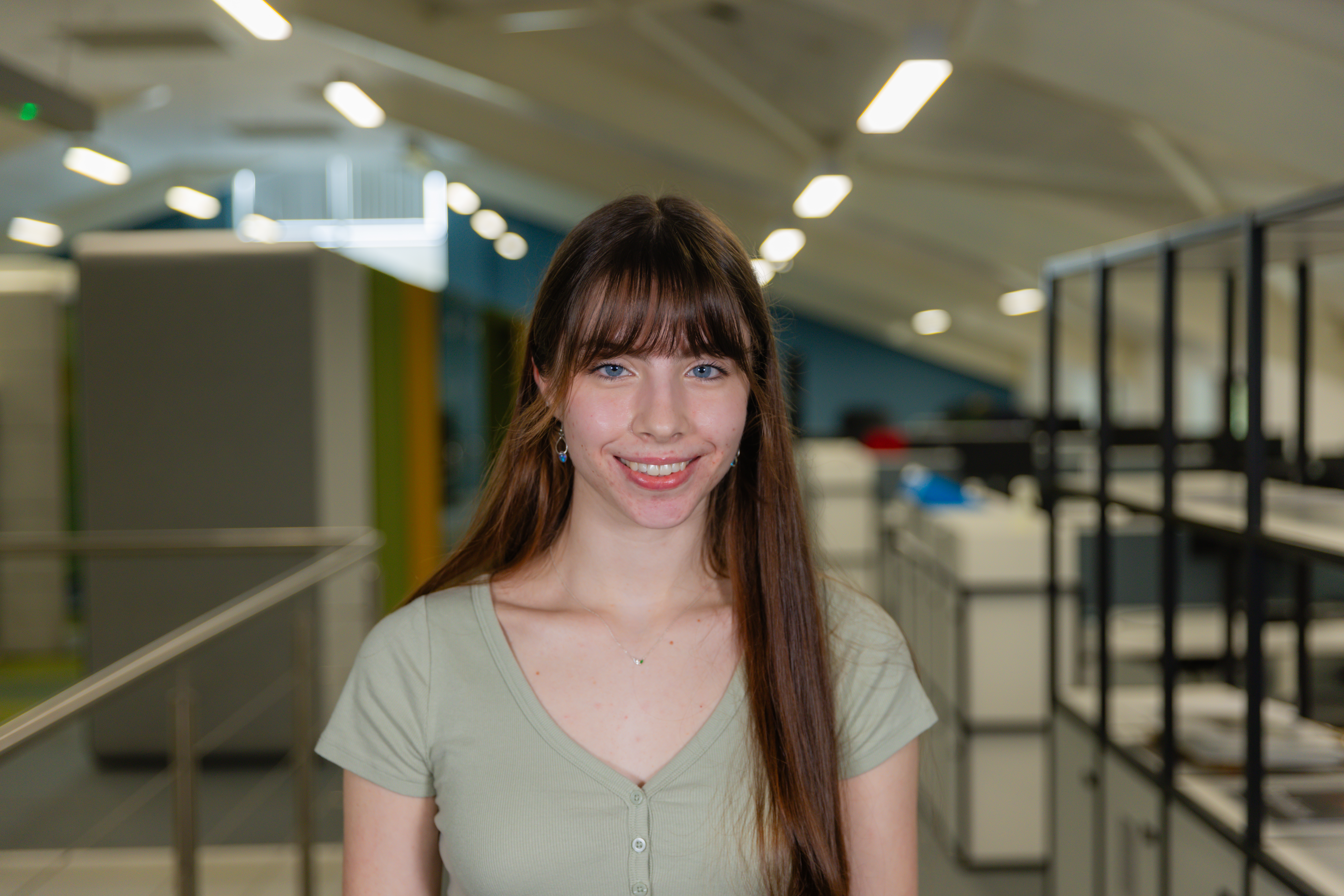 A smiling brunette woman in a green top.