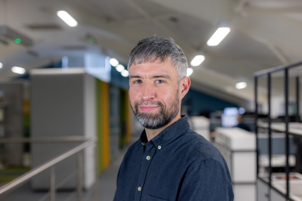 Headshot of Mick Roman, a smiling man in a navy shirt.