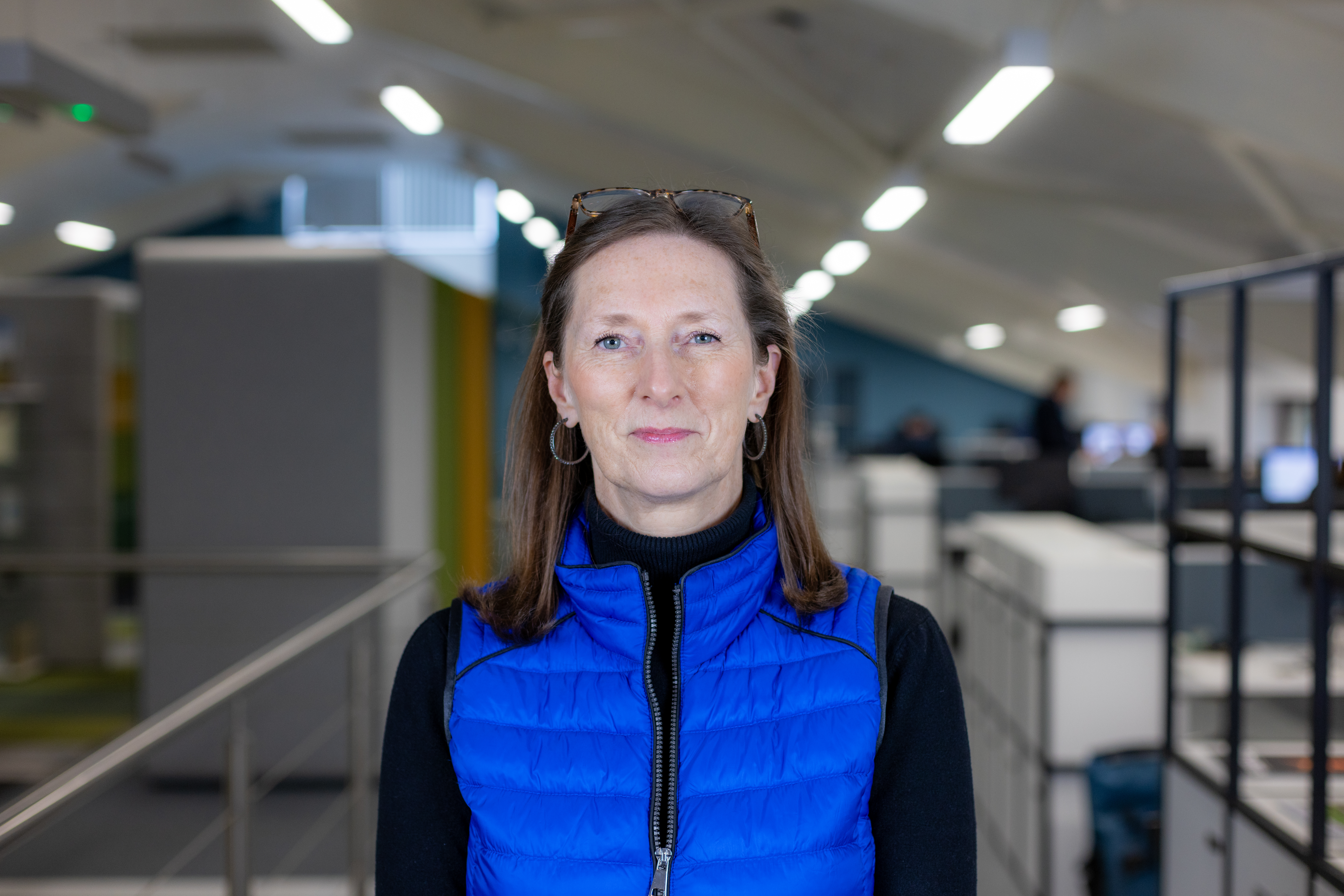 Headshot of Paula Wheldon, a brunette woman in a blue gilet and black top