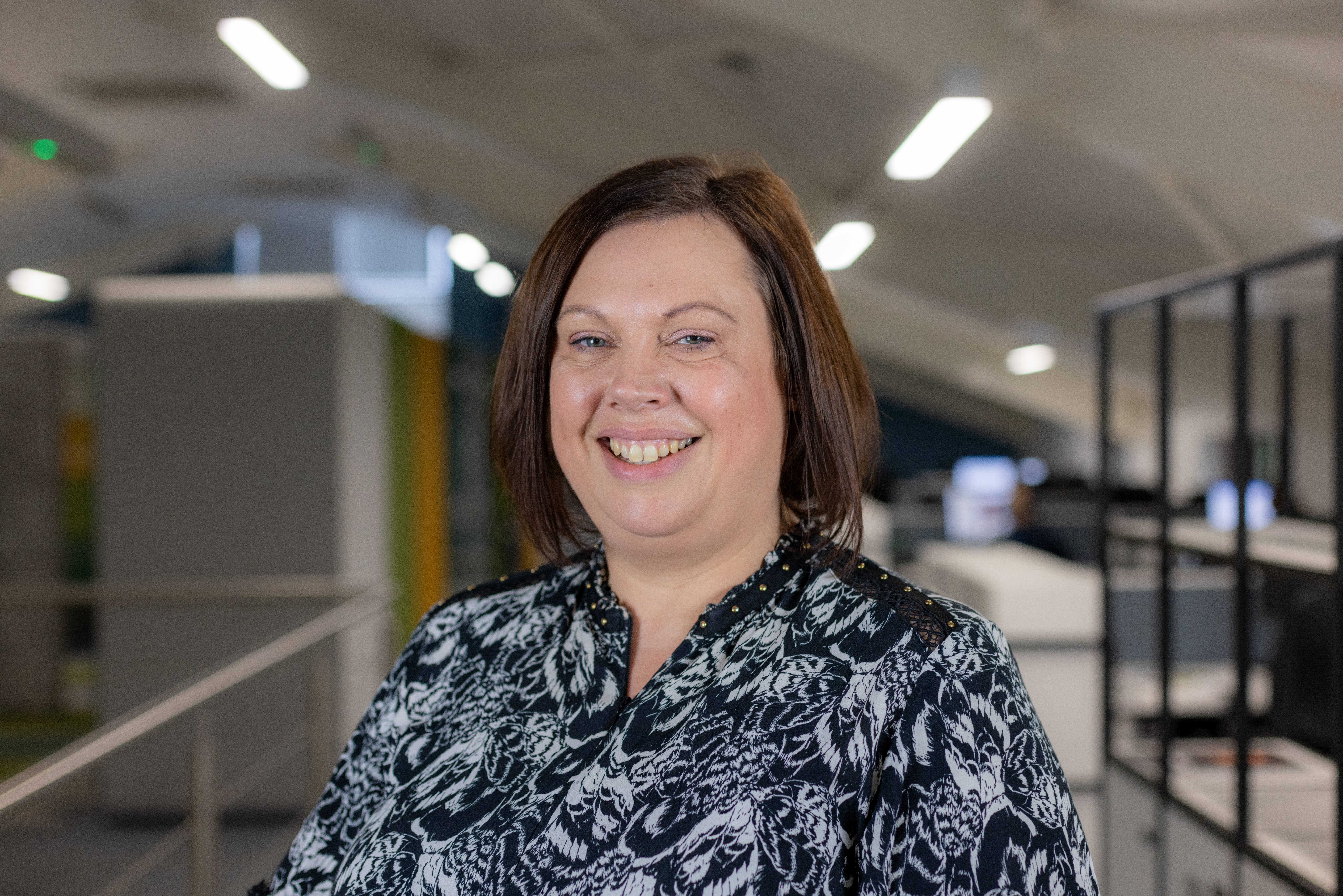 Headshot of Victoria Blake, a smiling brunette woman in a black and white shirt.