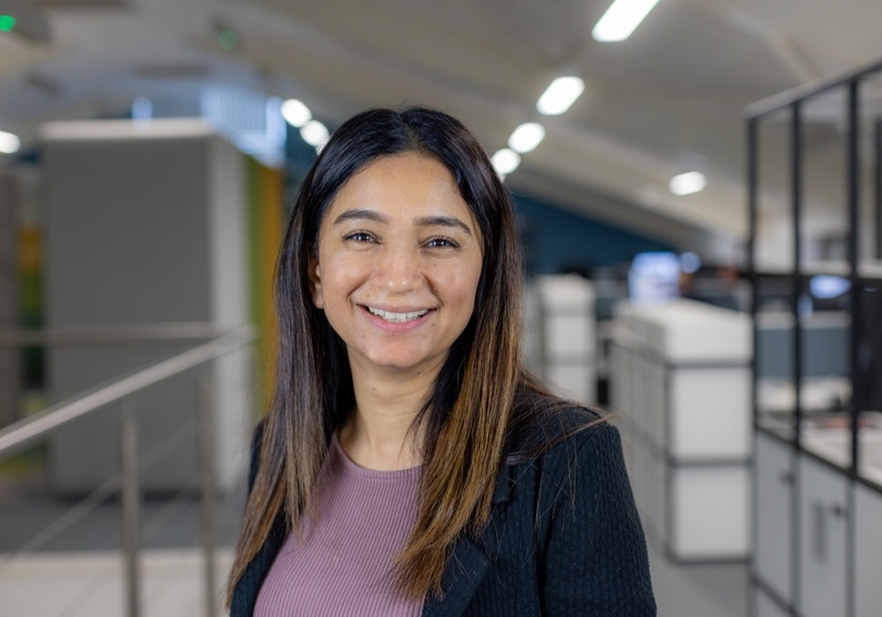 Headshot of Ambreen Jahangir, a smiling woman with brown hair in a purple top and black blazer