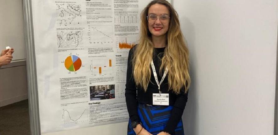 Danielle Bird is standing in front of a conference poster
