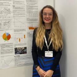 Danielle Bird is standing in front of a conference poster